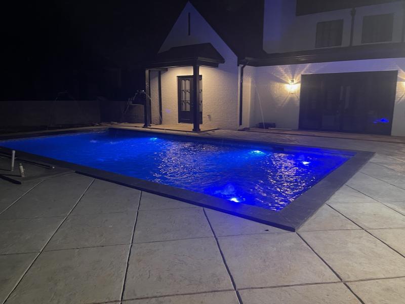Custom in-ground pool with underwater LED lighting, built by Robinson Inc, glistening at night